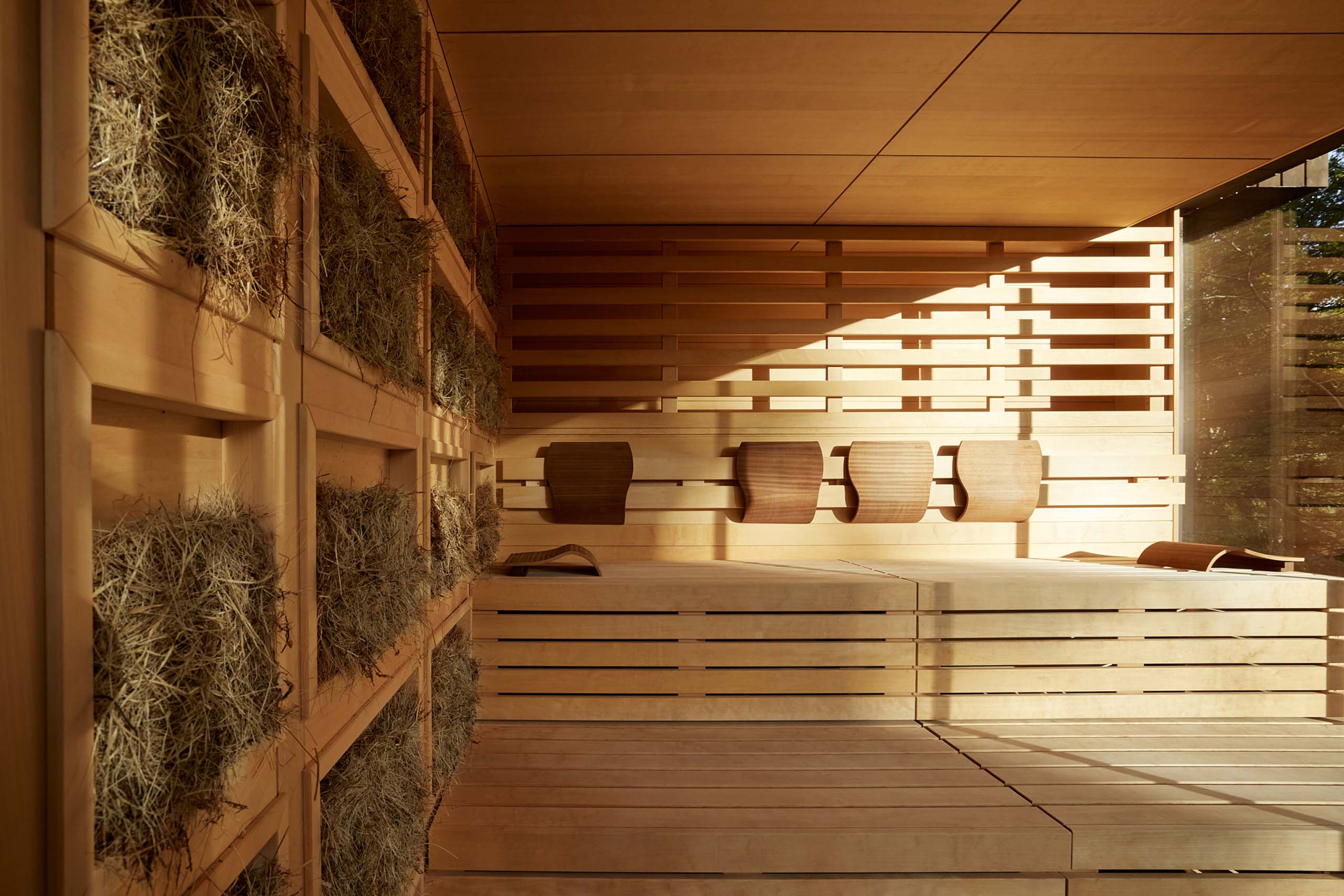Holzinterieur einer Sauna mit Heukissen an der Wand und Sonnenlicht